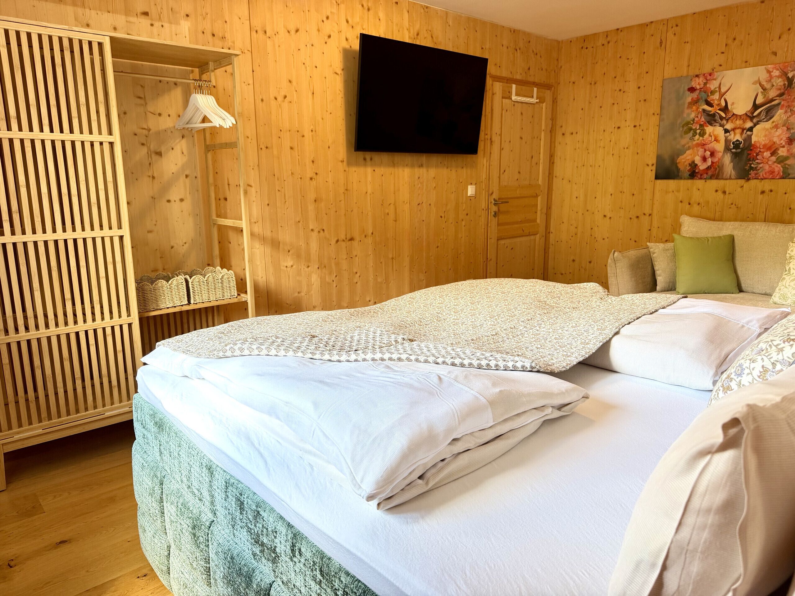 A wooden-paneled room with a bed, a TV, and a painting.