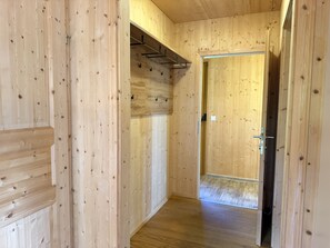 A wooden interior hallway with a door leading to another room.