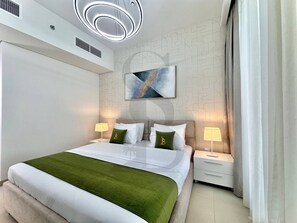 A modern hotel room with a large bed, two bedside tables, a wall-mounted artwork, and a ceiling light fixture. - Amazing Water View Luxury 2 Br Prime Location (Dubai)