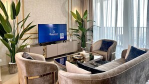 Un salon moderne doté d’un grand téléviseur à écran plat, de sièges confortables et de grandes fenêtres.