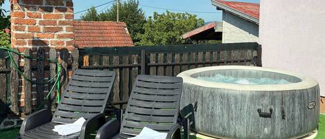 Ein Whirlpool, zwei Liegestühle, eine Backsteinmauer und ein Holzzaun.