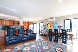 A spacious living area with a sofa, dining table, chairs, a rug, and a kitchen in the background. - 'The Wetlands' Holiday Home (Warrnambool)