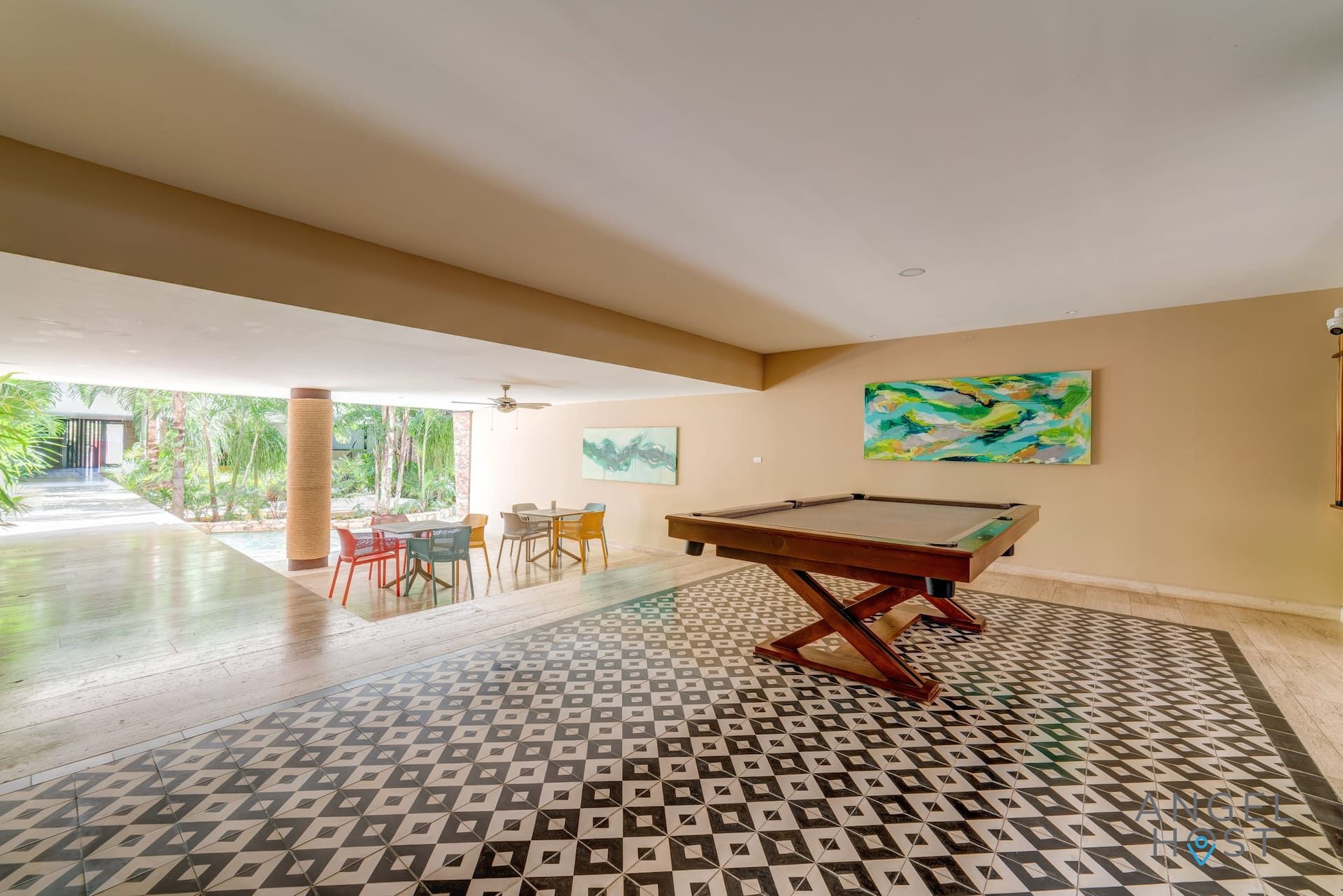 A pool table in a room with a patterned floor, a ceiling fan, and a view of a pool outside.