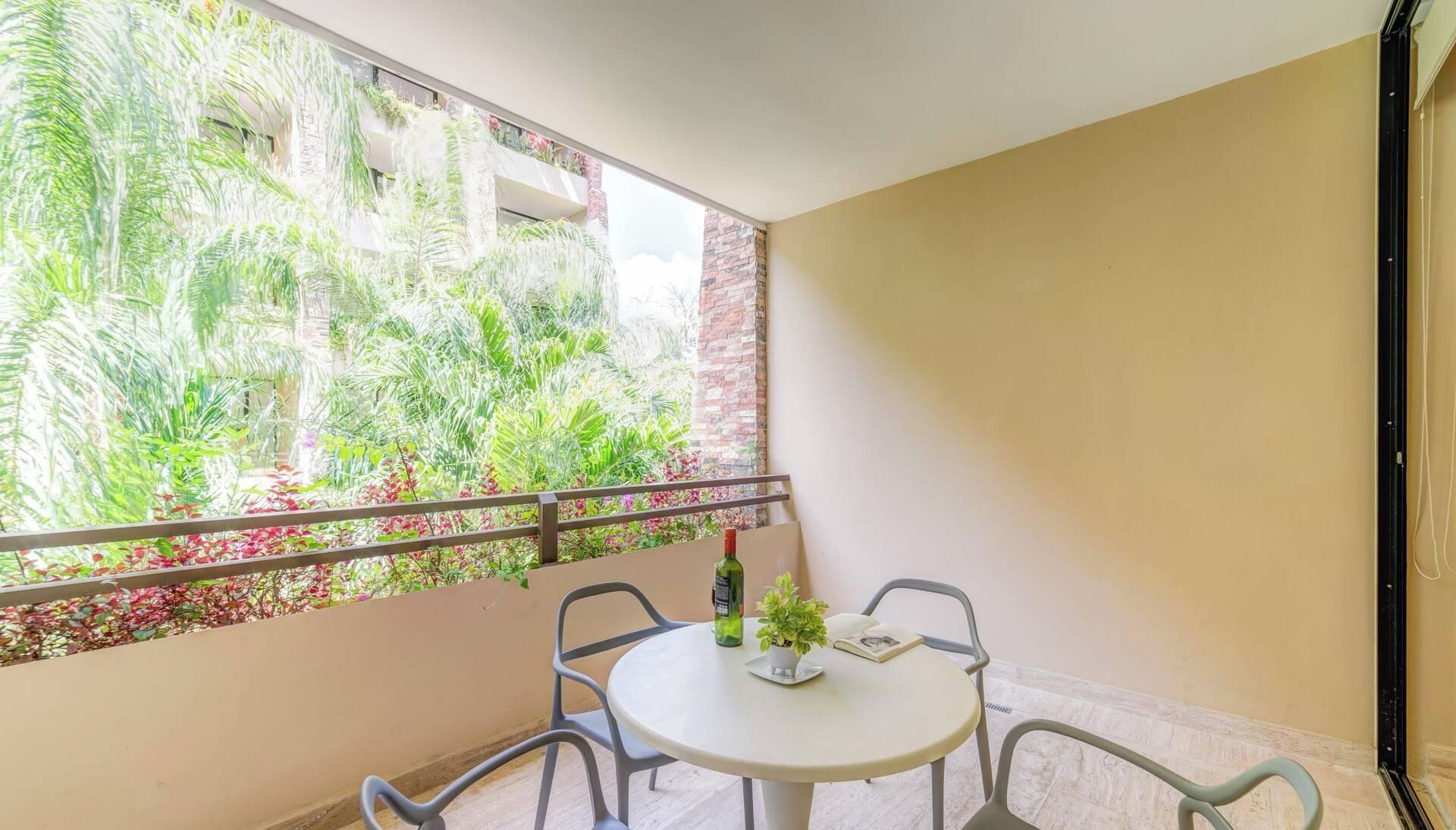 A balcony with a table, chairs, a bottle, and a potted plant.