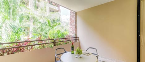 A balcony with a table, chairs, a bottle, and a potted plant.