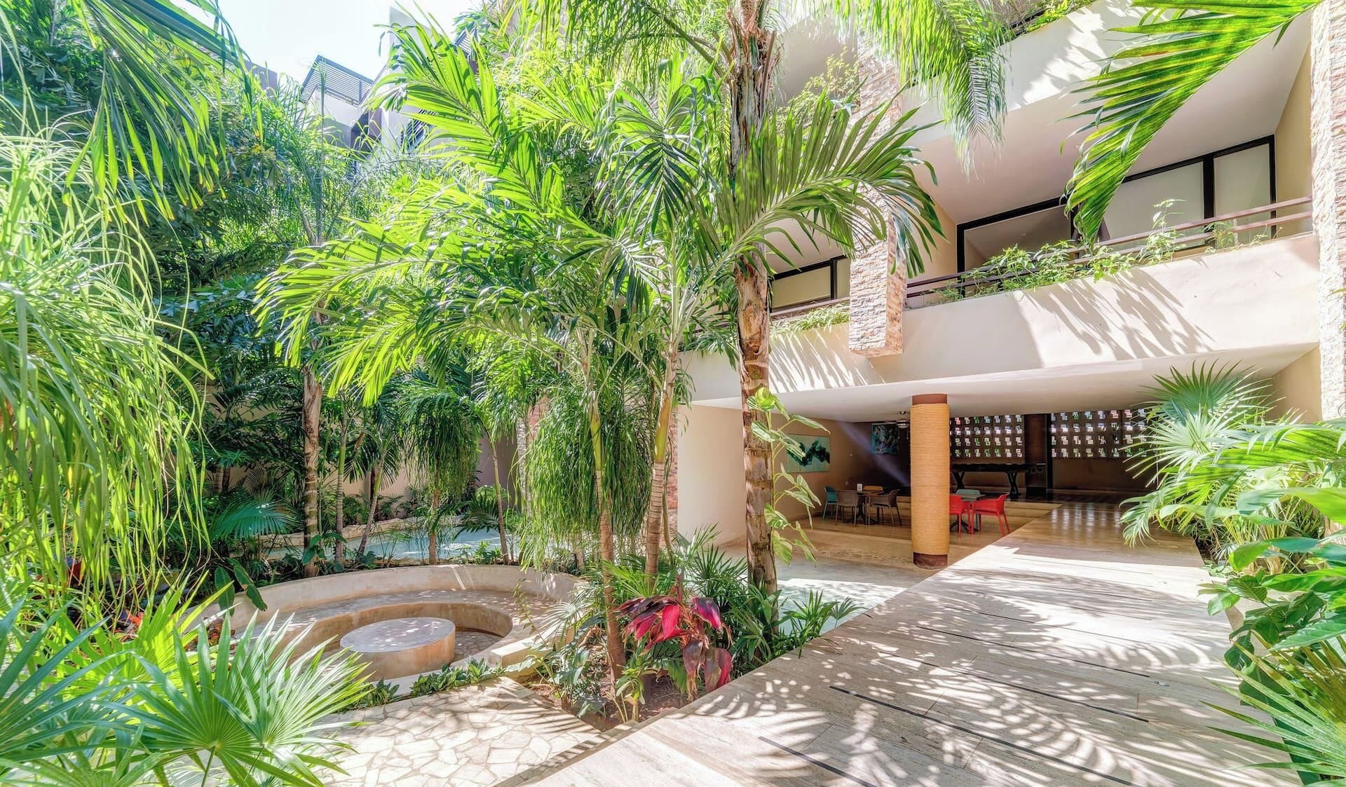 Un jardín interior con varios niveles, diversas plantas, una zona de estar y una piscina.