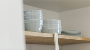 Une étagère avec des assiettes et des bols blancs empilés.