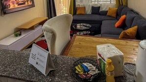 Una sala de estar con sofá, sillón, televisor y una mesita con una cesta y objetos encima.