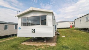 En campingvogn med en lille veranda, et vindue og en dør.