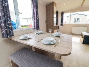 A dining area with a table set for four, including plates, glasses, and cutlery. - 42 Oak Green (Filey)
