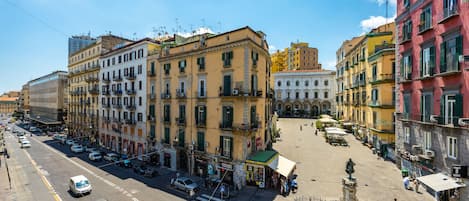 A street view of a city with buildings, a pedestrian crossing, and a statue in the foreground.
