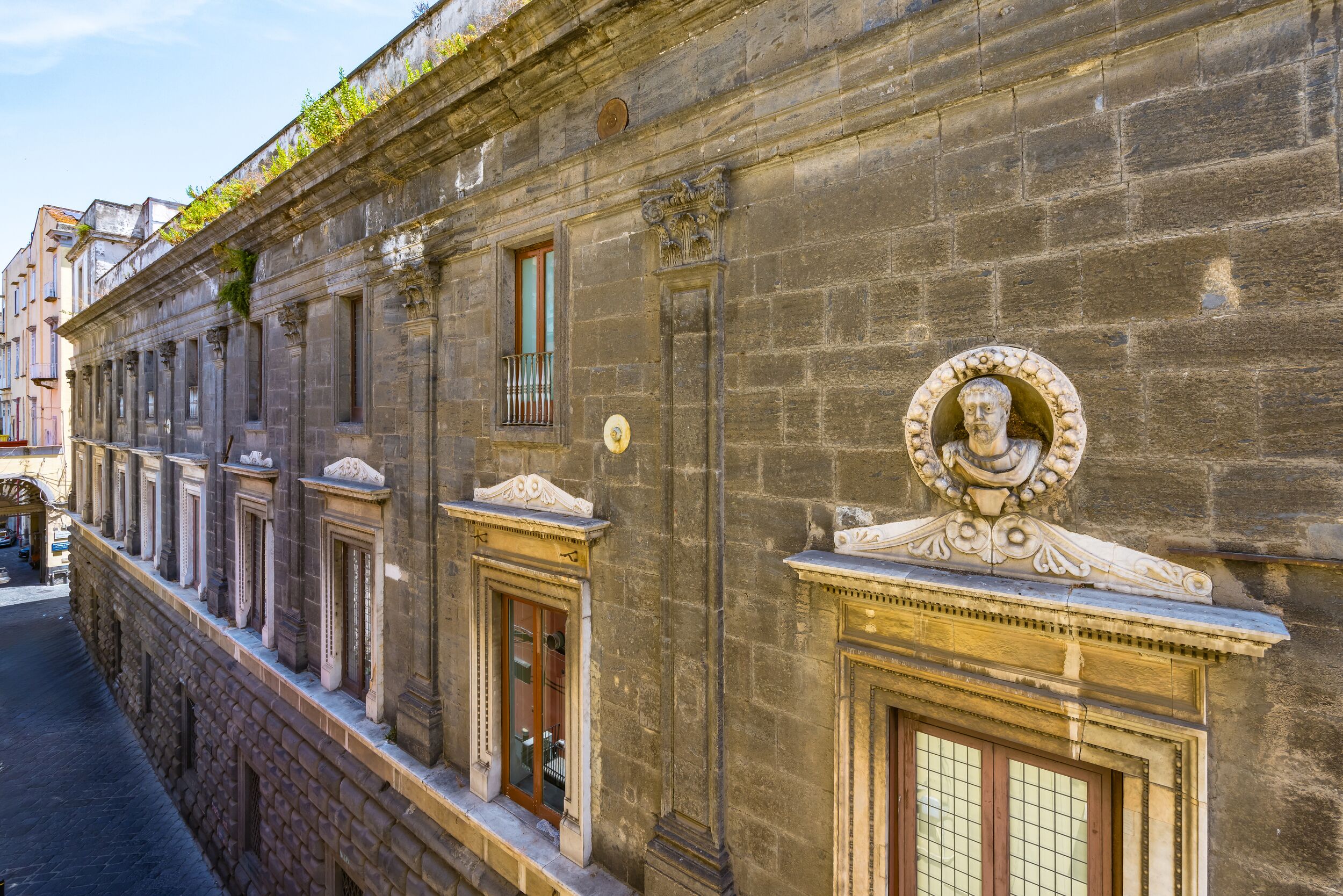Un edificio histórico con arquitectura clásica, que presenta trabajos en piedra ornamentados, una serie de ventanas y un relieve decorativo.