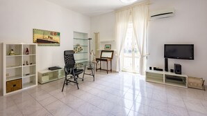 A modern living room with a glass desk, a black office chair, a flat-screen TV, and a radiator. - Pizzarchouse (Naples)