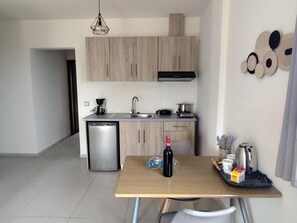 A modern kitchen with a dishwasher, a coffee maker, and a kettle on the counter.