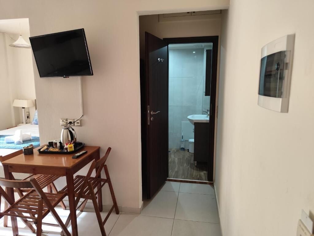 Hotelkamer met een eettafel, stoelen, een flatscreen televisie, een deur naar de badkamer en een aan de muur bevestigd schilderij.