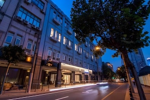 A multi-story hotel with a prominent entrance, large windows, and a tree-lined street. - Home Inn Selected (Shanghai)