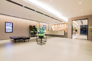 A modern lobby with a reception desk, seating area, and a large potted plant. - Home Inn Selected (Shanghai)