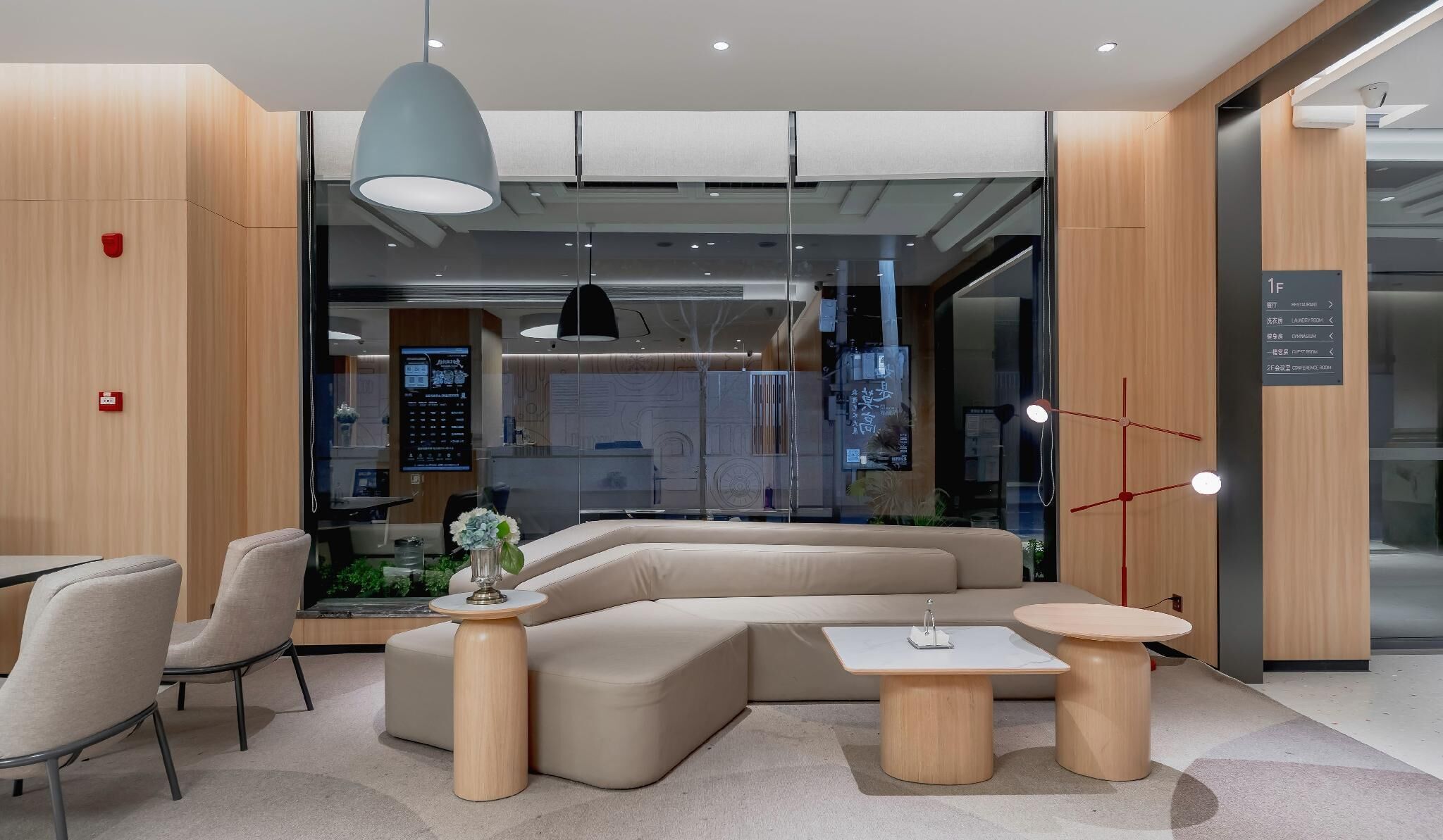 A modern lounge area with a sectional sofa, round tables, and a large pendant light.
