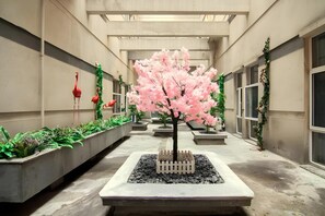 A corridor with planters, a central tree, and decorative flamingos.