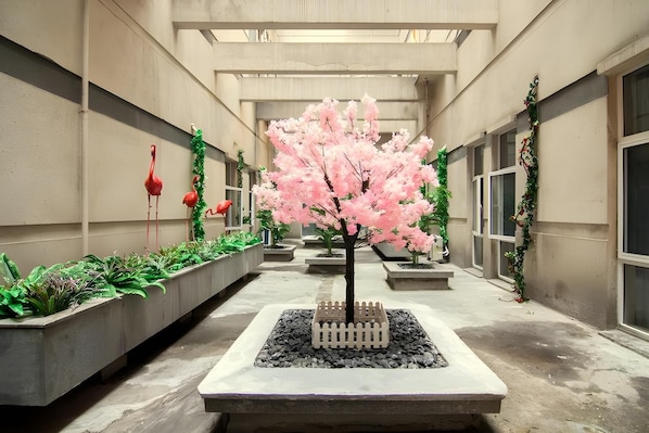 A corridor with planters, a central tree, and decorative flamingos. - Home Inn Selected (Shanghai)