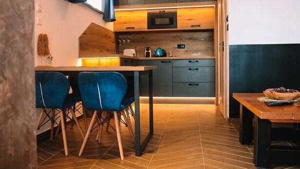 Eine moderne Küche mit Essbereich, Holzboden und blauen Stühlen.