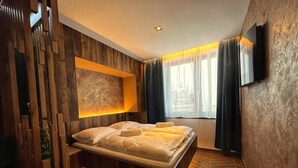 Ein modernes Schlafzimmer mit einem Bett, einem Wand-Fernseher und einem Fenster mit Vorhängen.