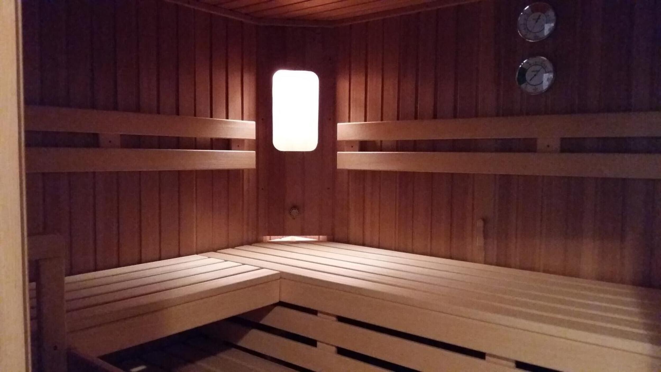 Een sauna met houten banken en een raam in het midden.