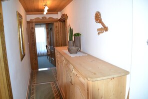 Ein hölzerner Flur mit einem Schrank, einem Spiegel, einer Topfpflanze und einer Wanduhr.