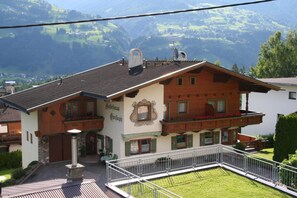Ein traditionelles Chalet mit Balkon, Steineingang und Blick auf die umliegenden Berge.