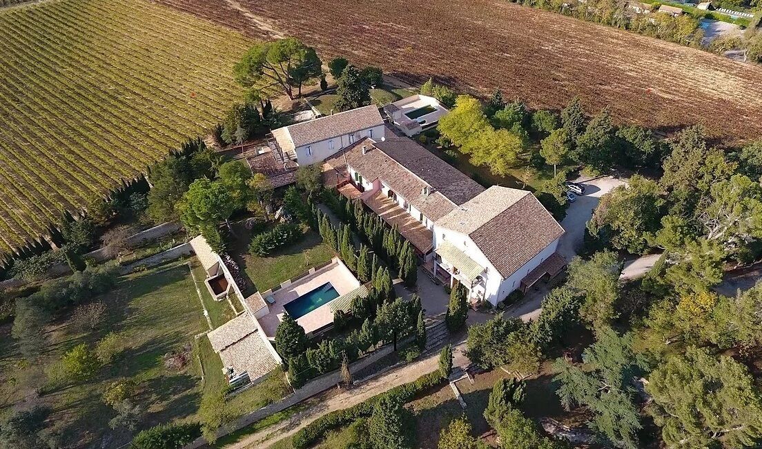 Luchtbeeld van een pand met een groot huis, een zwembad en omliggende velden.