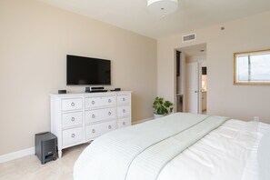 Ein Schlafzimmer mit Bett, Kommode, Fernseher und einer Pflanze.