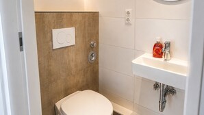 Ein modernes Badezimmer mit Toilette, Waschbecken und Spiegel.