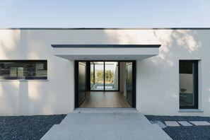 Ein modernes Gebäude mit Glastür, einem Betonweg und Blick ins Freie.