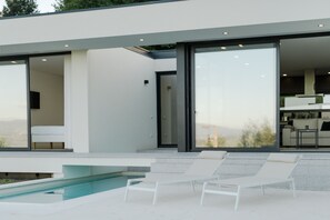 A modern outdoor pool area with lounge chairs, a clear view of the landscape, and a contemporary architectural design. - Feel Discovery Douro Living Villa I (Paços de Gaiolo)