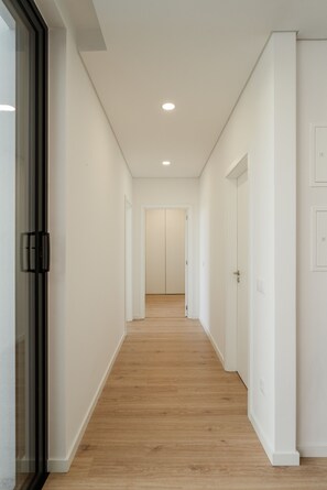 A hallway with wooden flooring, white walls, and doors leading to rooms. - Feel Discovery Douro Living Villa I (Paços de Gaiolo)