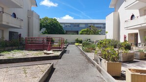 Ein Innenhof mit Kiesweg, Pflanzkübeln und einem roten Tor.