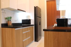 A modern kitchen with wooden cabinets, a black refrigerator, a microwave, and a coffee maker.