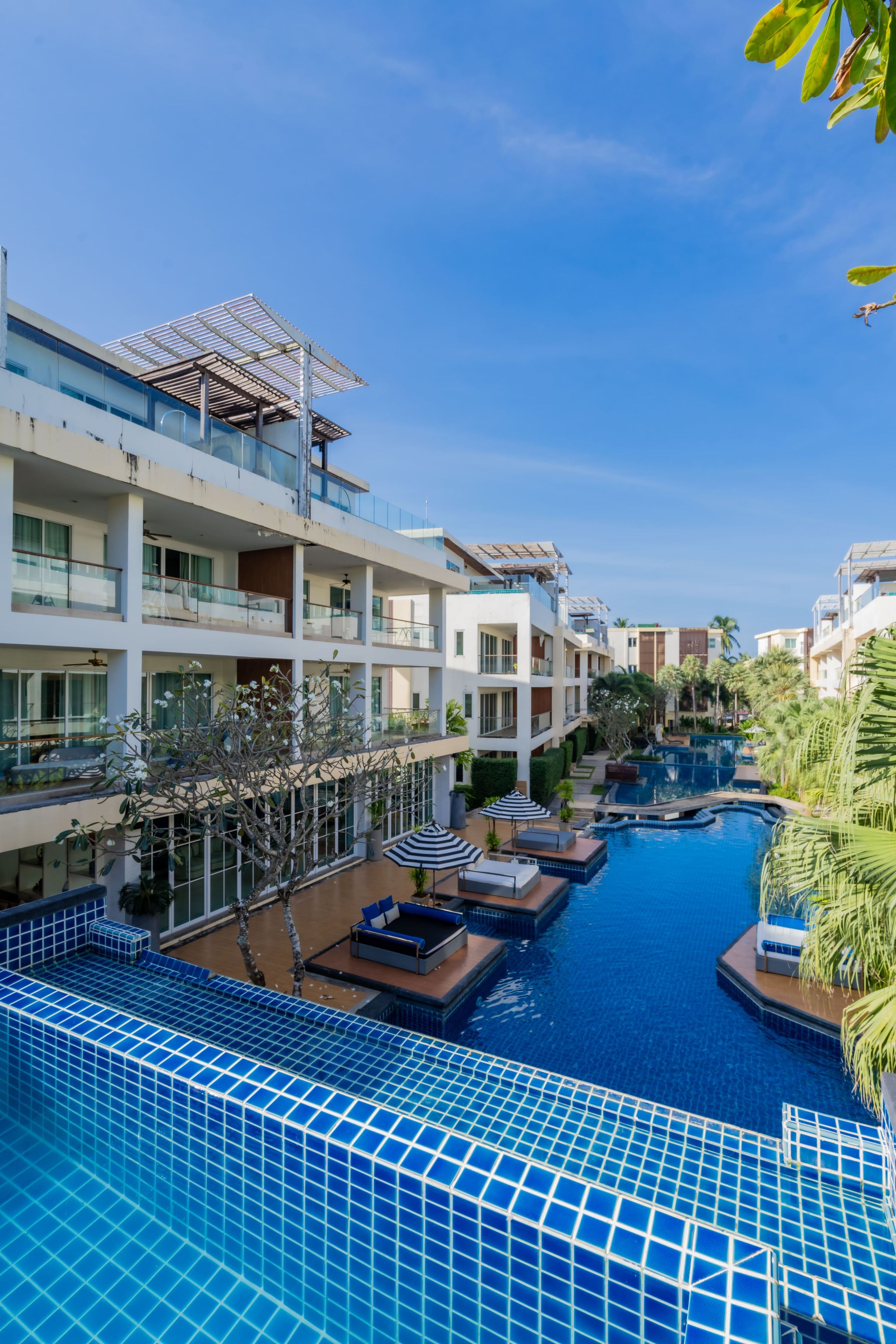 A resort with a swimming pool, multiple balconies, and a clear sky.