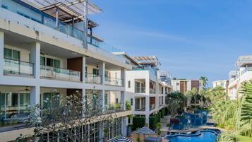 A resort with a swimming pool, multiple balconies, and a clear sky.
