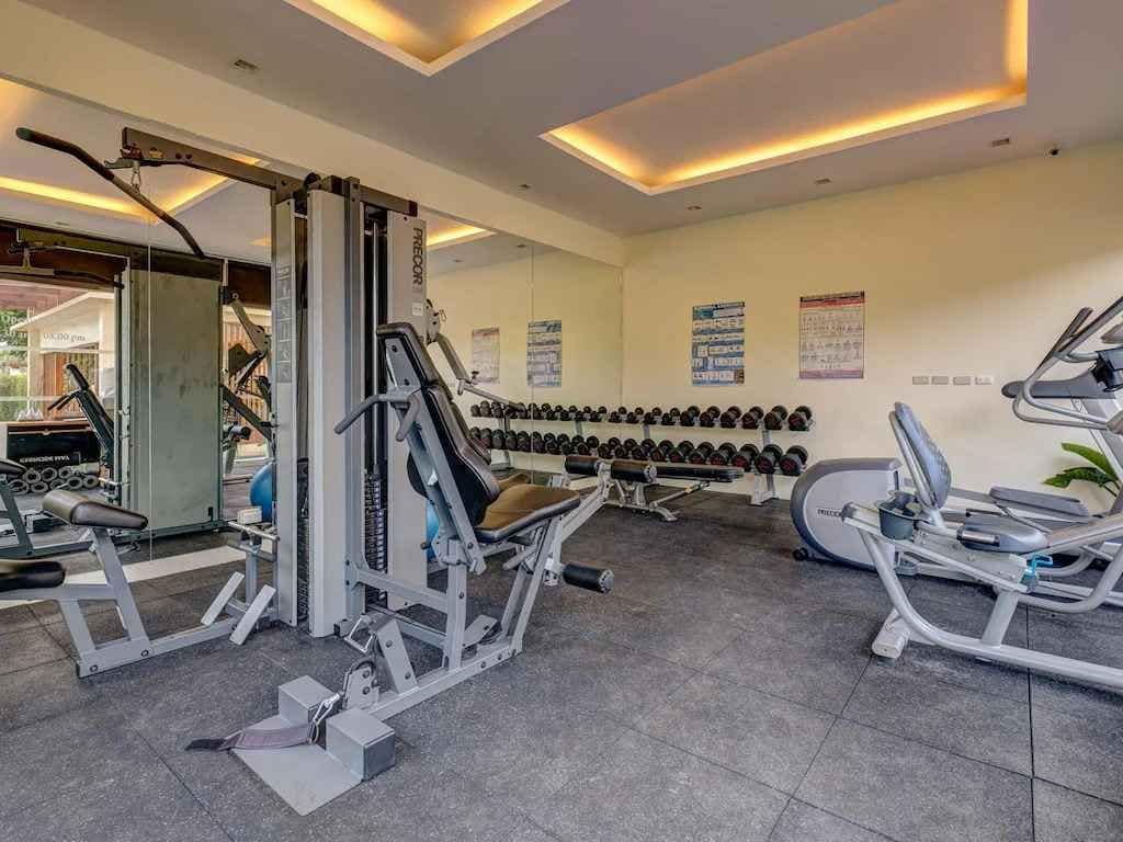 Un gimnasio con equipo de ejercicio variado, incluyendo máquinas de pesas y mancuernas.
