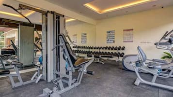 Un gimnasio con equipo de ejercicio variado, incluyendo máquinas de pesas y mancuernas.