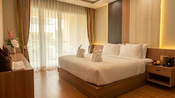 Una habitación de hotel con una cama grande, mesitas de noche, un escritorio y una ventana con cortinas.