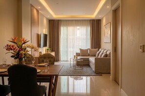 A modern living room with a dining area, a sofa, a TV, and a large window with curtains.