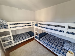 Une chambre avec un lit superposé, un plafond blanc et un plancher en bois.