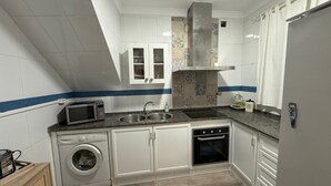 A kitchen with white cabinets, a microwave, a washing machine, a sink, and a stove.