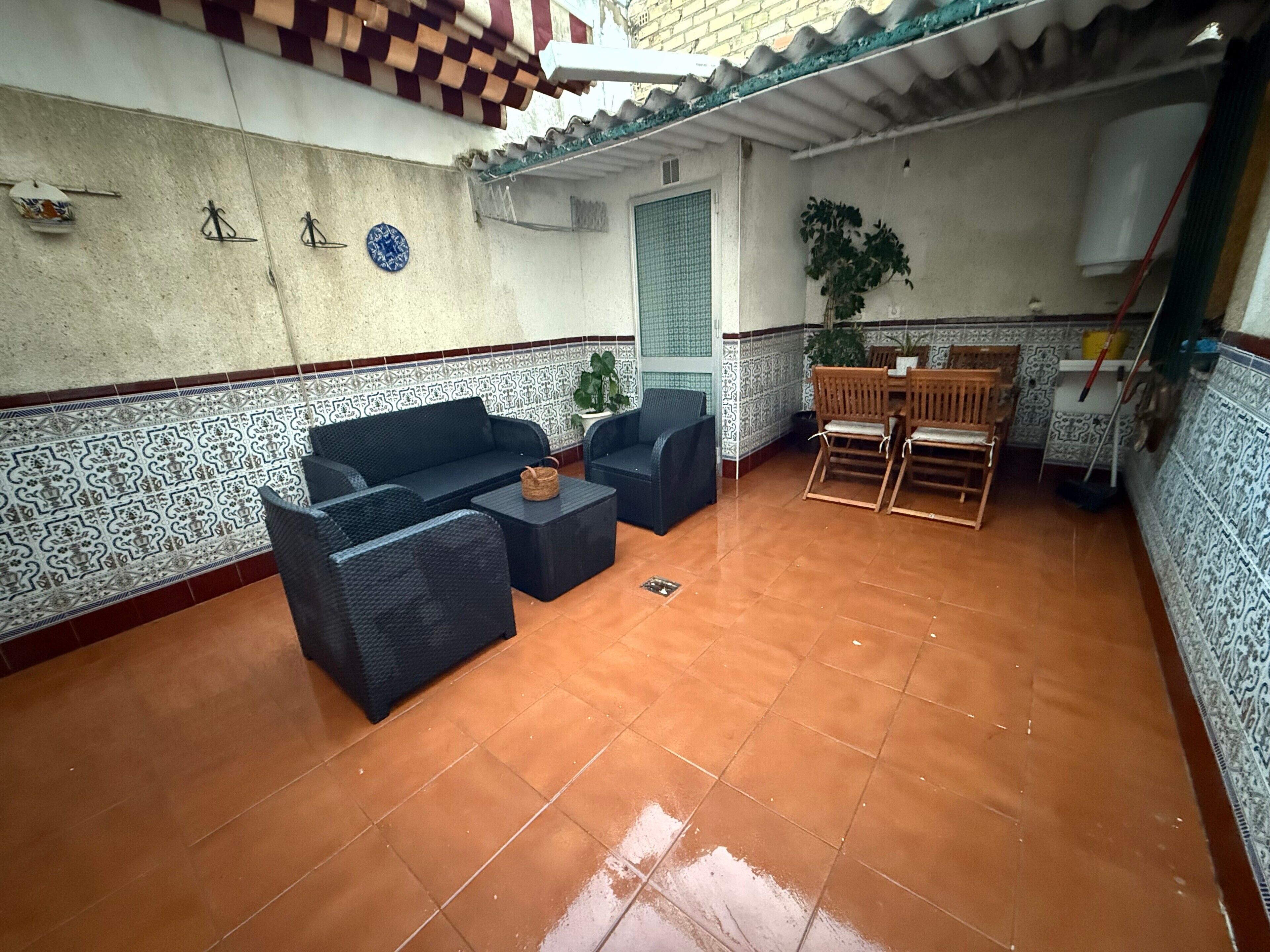 A patio area with a sofa set, a small table, and a wooden chair.