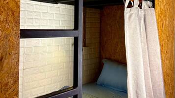 A bunk bed with a mattress on top and a lower bunk. There is a wooden wall with a textured pattern and a white brick wall.