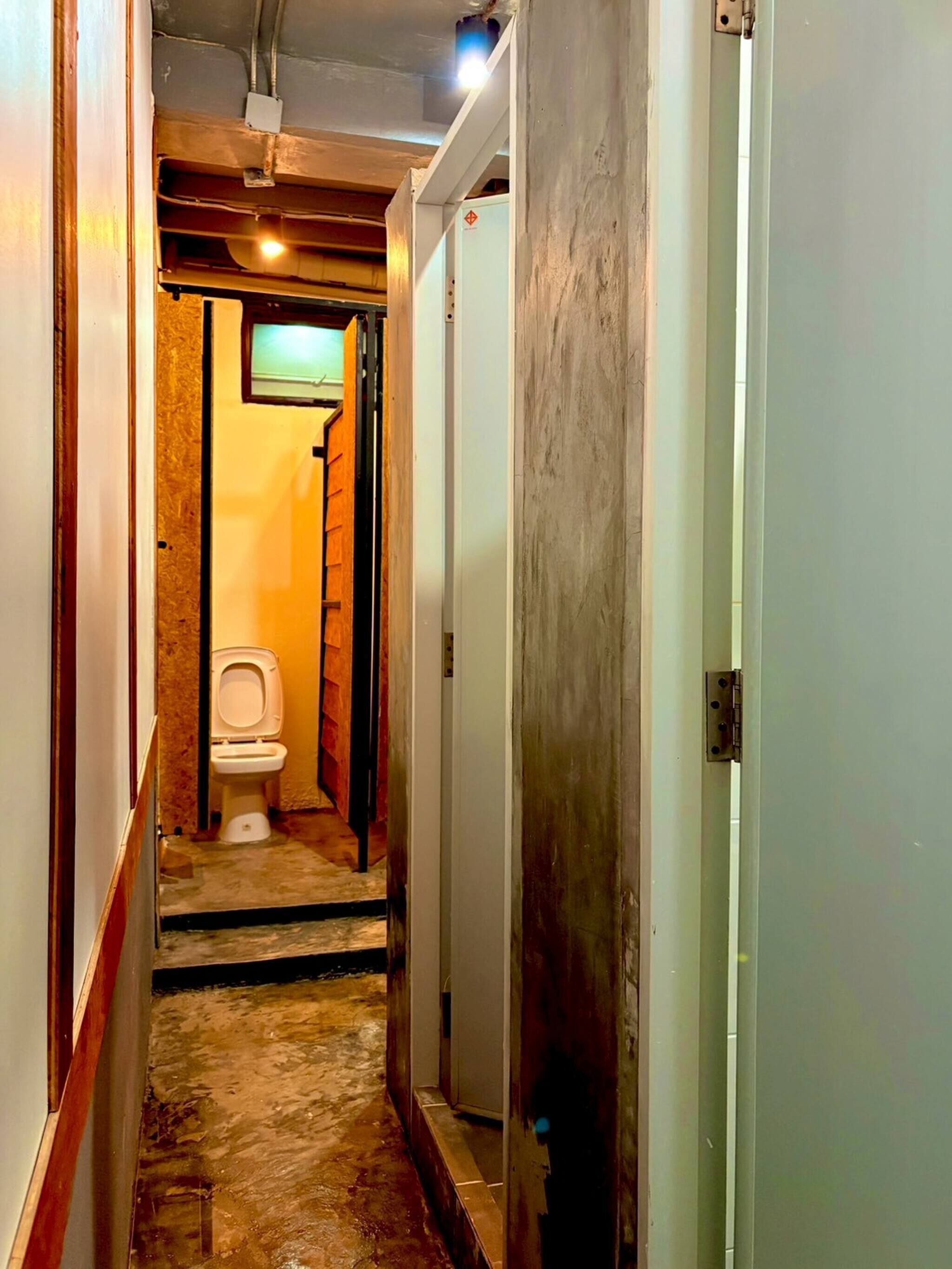 A narrow hallway with a toilet and a door on the right.