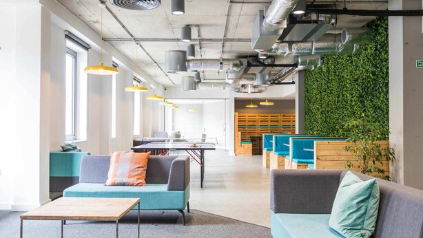 A modern office space with seating areas, a ping pong table, and a green wall. - Student Only The Cam Foundry (Cambridge)