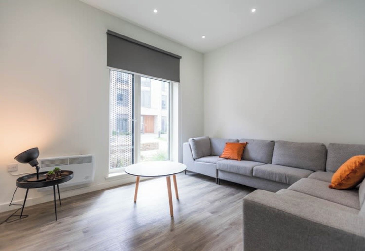 A modern living room with a grey sofa, a small round table, and a floor lamp.